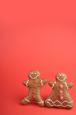 Gingerbread man and Gingerbread lady decorated colored icing. Holiday cookie in shape of man and lady in red backgroundの写真素材