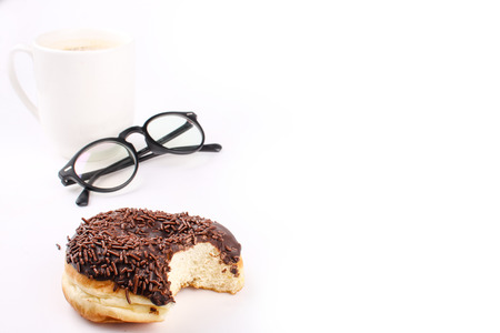 chocolate doughnut been eaten concept with spectacles and a hot drink in the frameの写真素材