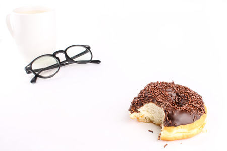 chocolate doughnut been eaten concept with spectacles and a hot drink in the frameの写真素材