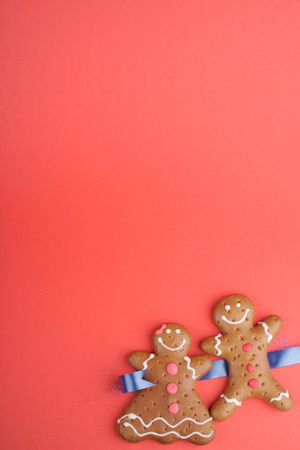 Gingerbread man and Gingerbread lady decorated colored icing. Holiday cookie in shape of man and lady in red backgroundの写真素材