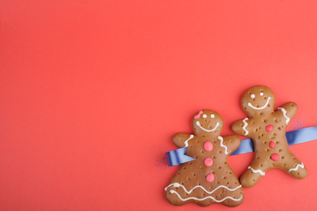Gingerbread man and Gingerbread lady decorated colored icing. Holiday cookie in shape of man and lady in red backgroundの写真素材