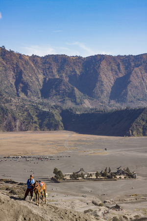 BROMO, INDONESIA - NOVEMBER 17: Local Tengger people with his horse at Mount Bromo waiting for a tourist for horse riding with background of Mount Penanjakan and Hindu temple Pura Luhur Poten, Bromo Indonesia 17 November 2015のeditorial素材