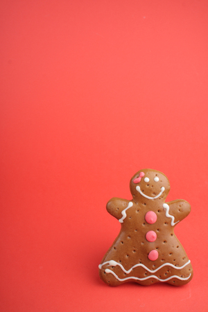 Gingerbread lady decorated colored icing. Holiday cookie in shape of  lady in red backgroundの写真素材
