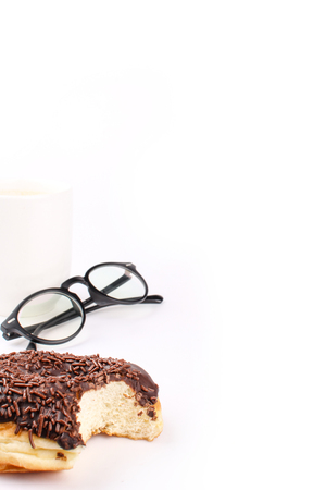 chocolate doughnut been eaten concept with spectacles and a hot drink in the frameの写真素材