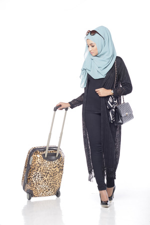 muslimah asian woman with her trolly bag wating and posing for people isolated in white backgroundの写真素材