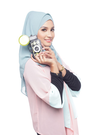 asian muslimah woman posing with a toy camera isolated in white backgroundの写真素材