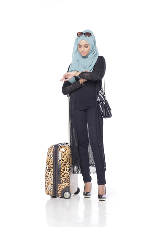 muslimah asian woman with her trolly bag wating and posing for people isolated in white backgroundの写真素材