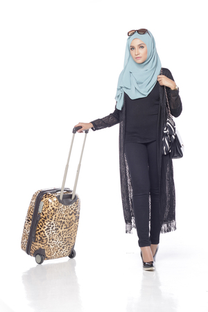 muslimah asian woman with her trolly bag wating and posing for people isolated in white backgroundの写真素材