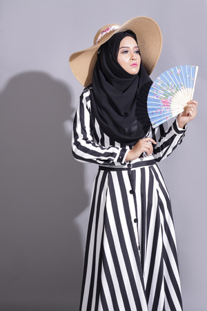 asian beautiful muslimah woman with eid attire light with sun on gray backgroundの写真素材