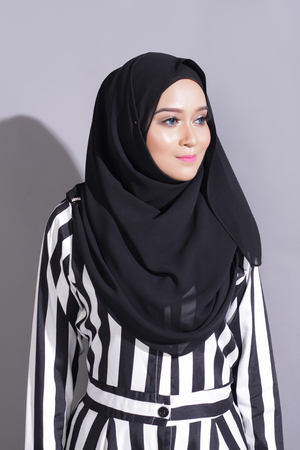 asian beautiful muslimah woman with eid attire light with sun on gray backgroundの写真素材