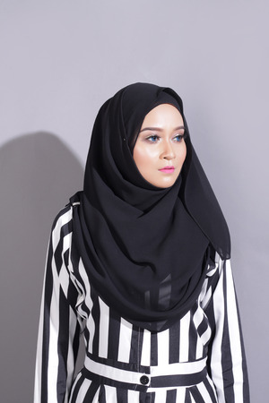 asian beautiful muslimah woman with eid attire light with sun on gray backgroundの写真素材