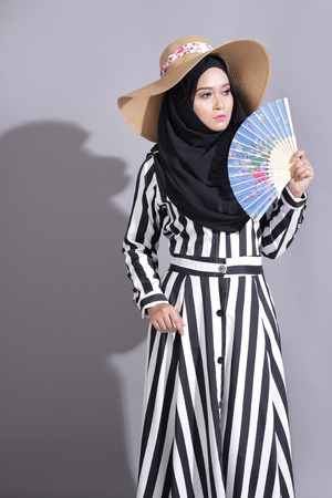 asian beautiful muslimah woman with eid attire light with sun on gray backgroundの写真素材