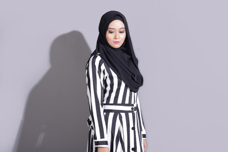 asian beautiful muslimah woman with eid attire light with sun on gray backgroundの写真素材