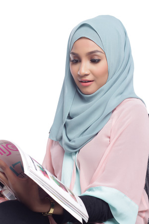 portrait of young asian muslimah woman reading a magazineの写真素材