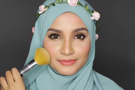 portrait of young asian beautiful muslimah woman doing a make over on her faceの写真素材