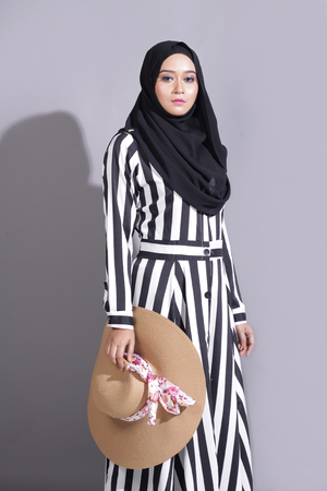 asian beautiful muslimah woman with eid attire light with sun on gray backgroundの写真素材