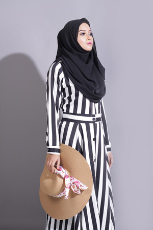 asian beautiful muslimah woman with eid attire light with sun on gray backgroundの写真素材