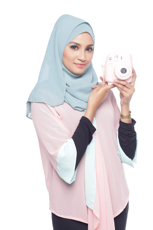 asian muslimah woman posing with a toy camera isolated in white backgroundの写真素材
