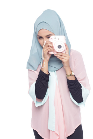 asian muslimah woman posing with a toy camera isolated in white backgroundの写真素材