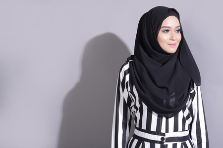 asian beautiful muslimah woman with eid attire light with sun on gray backgroundの写真素材