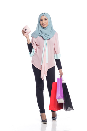portrait of asian muslimah woman with her shopping bag having fun with toy camera in white backgroundの写真素材