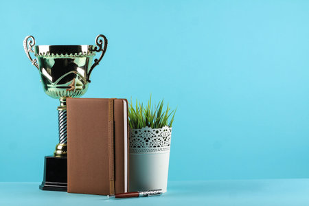 notebook planner and a trophy in pastel blue background