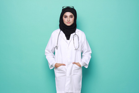 muslimah doctor holding a stethoscope isolated in turquoise  backgroundの写真素材