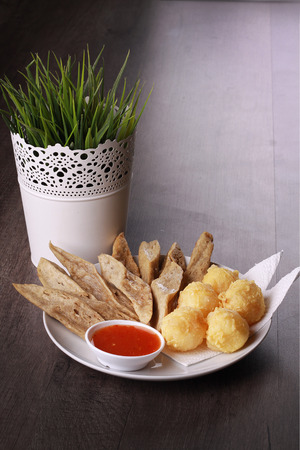 keropok lekor with fried yam served with chili sauce isolated on wooden backgroundの写真素材