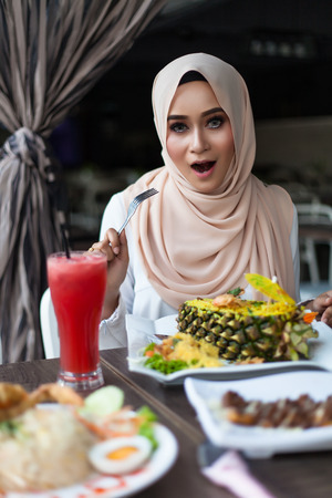 malay woman eating at cafe with juices and foodの写真素材