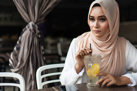malay woman eating at cafe with juices and foodの写真素材