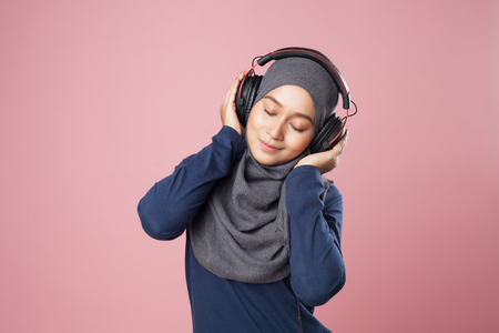 Young woman enjoying the music and relax with sport outfit on pink background.の写真素材