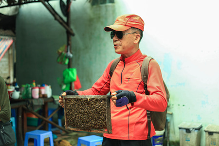 Ho Chi Minh City, Vietnam - 1 January 2018. Tourist from China holding a bee hive at Mekong delta trips.のeditorial素材