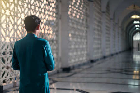 muslim doing religious praying at mosque with sunset flare in frameの写真素材