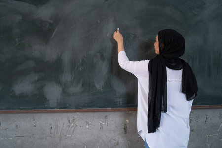 a teacher is teaching using a chalk at the blackboard with some expressions