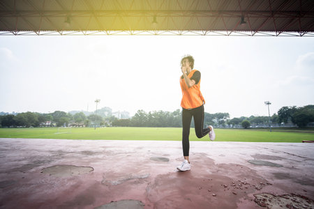 athelic asian woman running inside stadium