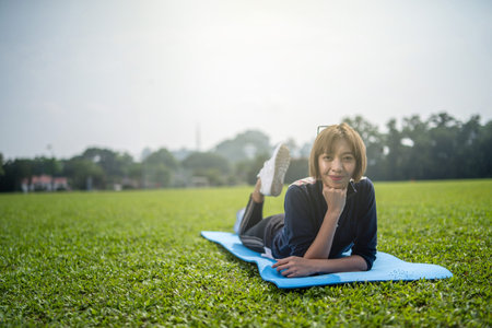 asian woman with yoga mat in green field