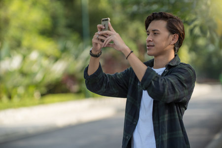 young handsome asian man with smartphone in park