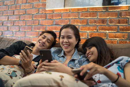 young asian chilling indoor with smartphone