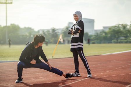 asian muslim couple doing exercise at stadium tracks with sport attireの写真素材