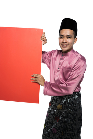 asian man with malay traditional attire holding a promotional cardの写真素材