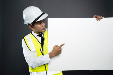 asian construction man holding a promotional card for copy space in gray backgroundの写真素材