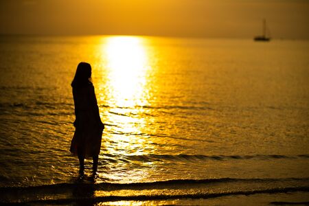 asian woman standing looking at the wonderful yellow sunsetの写真素材