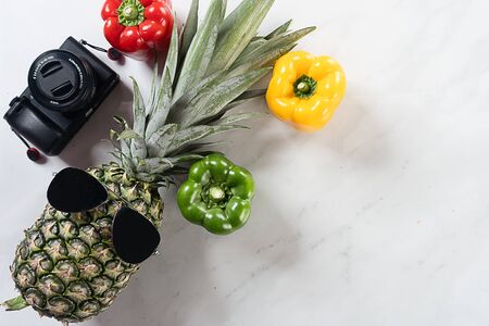 pineapple, capsicum and camera with marble backgroundの写真素材