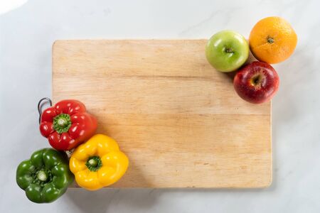 fruit and capsicum on chopping board with white marble backgroundの写真素材