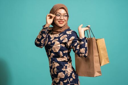 This woman is enjoys shopping a lot. At Turquoise color backgroundの写真素材