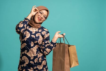 This woman is enjoys shopping a lot. At Turquoise color backgroundの写真素材