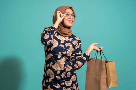 This woman is happy to be shopping. At Turquoise color backgroundの写真素材