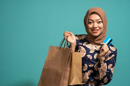 This woman is enjoys shopping a lot with use credit card . At Turquoise color backgroundの写真素材