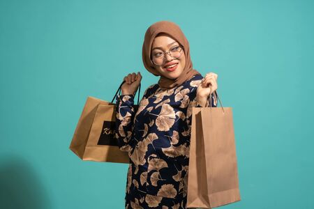 This woman is enjoys shopping a lot. At Turquoise color backgroundの写真素材