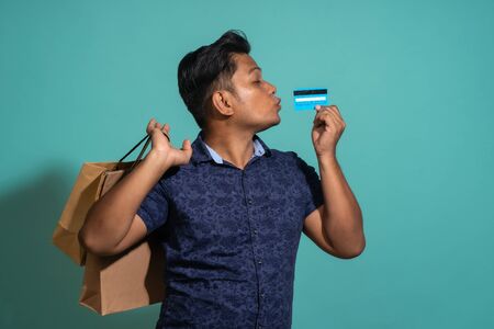 The man was excited to shopping with use the credit card . At Turquoise color backgroundの写真素材